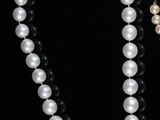 two necklaces with pearls and black onyx beads on a black background