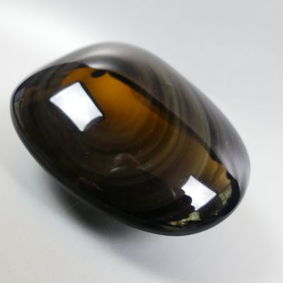 une photo d'un objet en verre brun posé sur une surface blanche