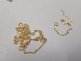 two pieces of gold chains and a necklace on a table
