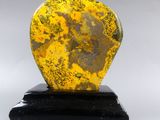 yellow and black heart shaped stone on black base on white background