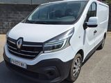 La camionnette blanche est garée sur le parking, à côté d'un mur de briques.