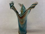 a glass vase with a bird on it on a table