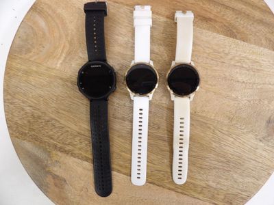 three watches are sitting on a round wooden table with a white strap