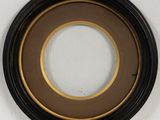 black and gold framed picture of a round mirror on a white wall