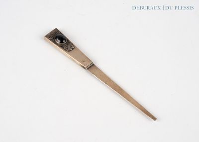 un petit objet métallique posé sur une surface blanche