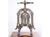une cafetière à piston ancienne en métal argenté, posée sur un socle en bois