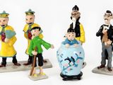 four figurines of different people standing next to each other