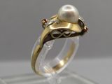 a close up of a ring with a pearl and diamonds on it