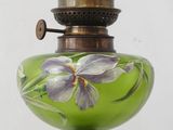 a green glass lamp with purple flowers painted on it