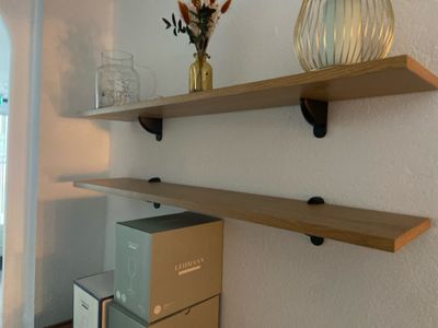 two shelves on the wall with vases and boxes on them