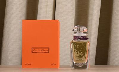 une boîte orange posée à côté d'un flacon de parfum sur une table