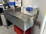 un évier en inox dans une cuisine avec des poubelles rouges posées sur le plan de travail