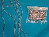 a close up of a necklace and a bag of beads on a blue surface