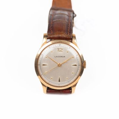 gros plan d'une montre sur une surface blanche avec un bracelet marron