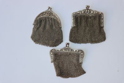 trois porte-monnaie en métal argenté et un porte-monnaie à chaîne posés sur une surface blanche