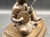bronze figurine of a boy playing a musical instrument on a marble base