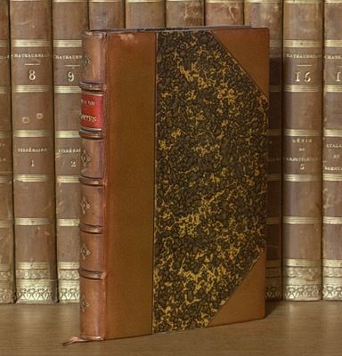 un livre posé sur une étagère, devant une pile de livres