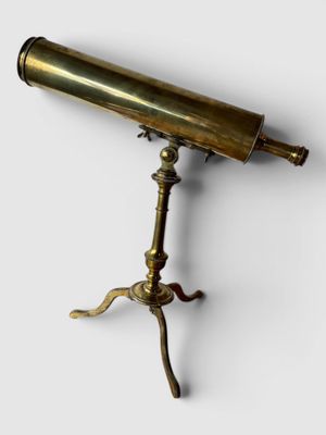un télescope ancien en laiton posé sur un trépied, sur fond blanc