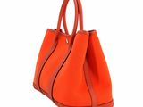 an orange handbag on a white background with a brown handle