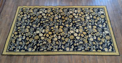 un tapis noir orné de fleurs jaunes et bleues posé sur un parquet