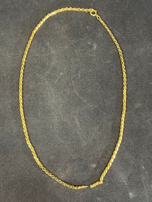 a gold necklace with a chain on a black surface