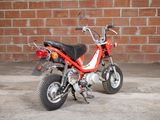 a small red motorcycle parked in front of a brick wall