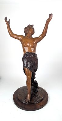 statue en bronze représentant un homme tenant une croix, posée sur un socle en marbre