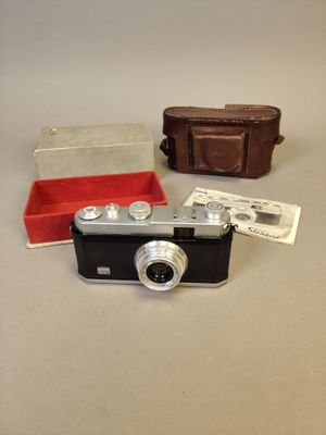 un petit appareil photo posé sur une table à côté d'un portefeuille