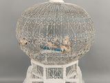 une cage à oiseaux blanche avec un oiseau à l'intérieur