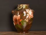 un vase avec des fleurs peintes dessus, posé sur une table
