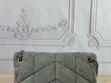 grey quilted purse with gold chain strap on a wooden table