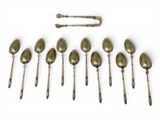 six spoons and a spoon rest in a row on a white surface