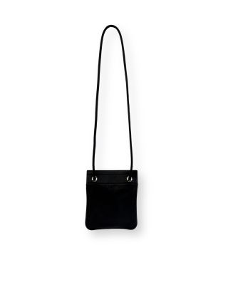 Le petit sac noir est accroché à un mur blanc.