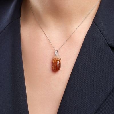 a close up of a woman wearing a necklace with an orange stone