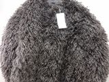 grey fluffy coat hanging on a hanger on a white wall