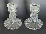 une paire de bougeoirs en verre transparent posés sur une surface noire