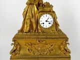 a gold clock with a statue on top of it