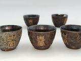 four silver cups are lined up in a row on a white surface