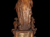 an old statue of a man holding a child on a wooden base