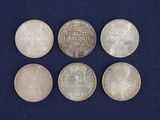 six different types of silver coins on a blue cloth