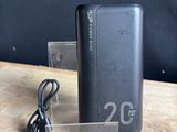 une batterie externe noire posée sur une table, à laquelle est branché un chargeur