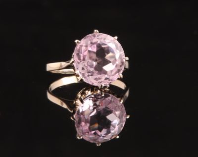 un gros plan d'une bague en pierre rose posée sur une surface noire