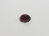 a close up of a red garnet stone on a white surface