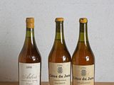 trois bouteilles de vin sont alignées sur une table en bois