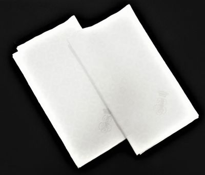 two white napkins on a black surface with a black background