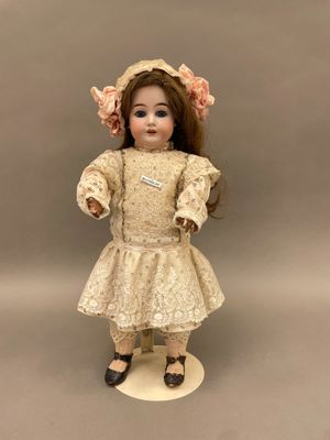 une poupée ancienne en porcelaine représentant une jeune fille vêtue d'une robe et d'un bonnet