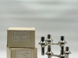 a pair of silver candles sitting on top of a white table