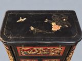 a black and gold chest of drawers with flowers on it