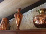 three copper vases sitting on a shelf in a room