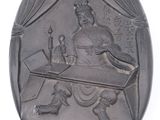 an image of a silver oval plaque with a man sitting at a desk